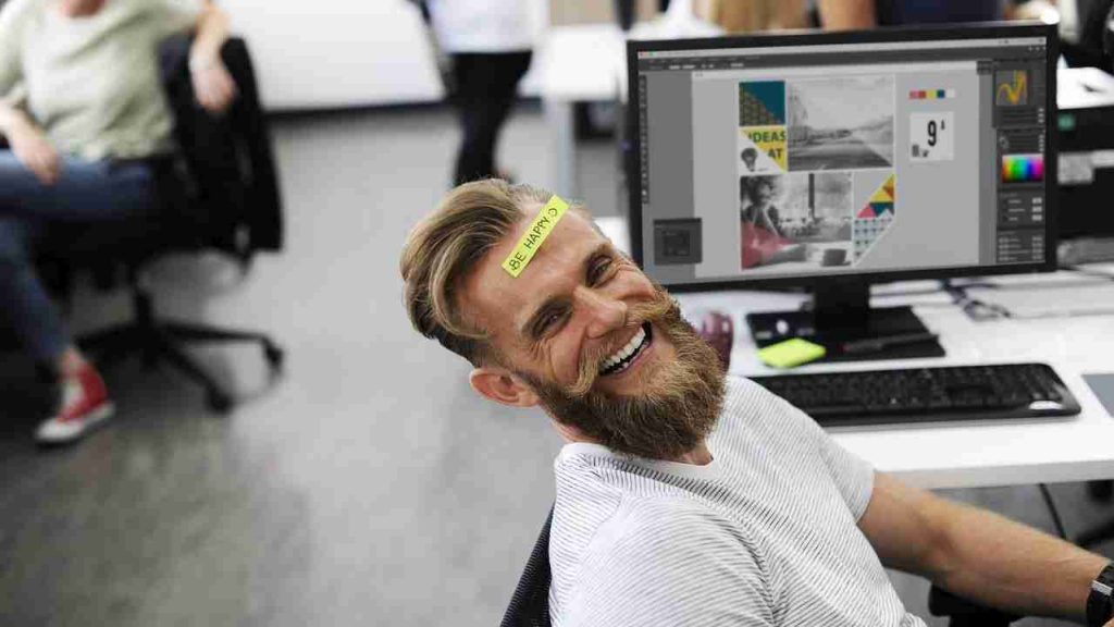 Homem sorrindo com etiqueta colada na testa dizendo "be happy".