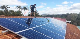 homem lavando painéis solares num telhado