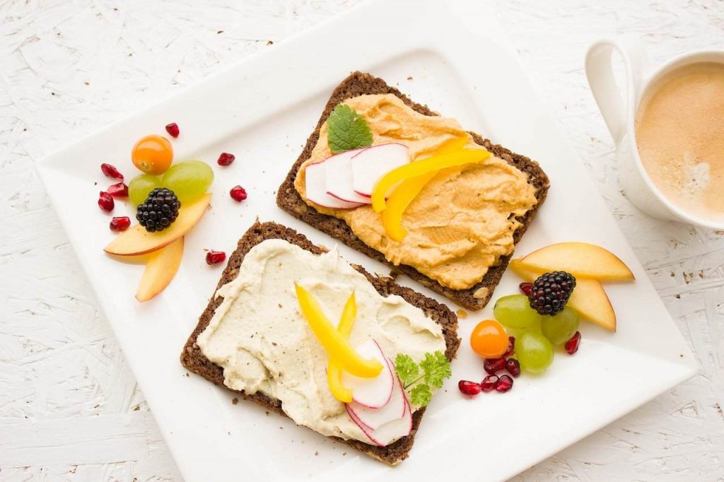 fatias de pão barradas com creme vegetal e com frutas e legumes