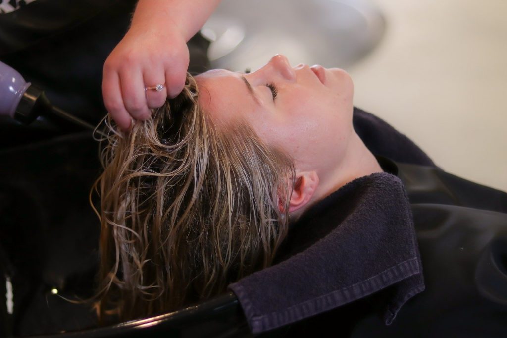 mulher secando cabelo de outra mulher em salão de beleza