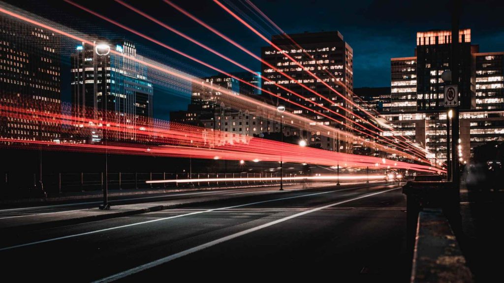 vista noturna de uma avenida entre prédios de uma cidade